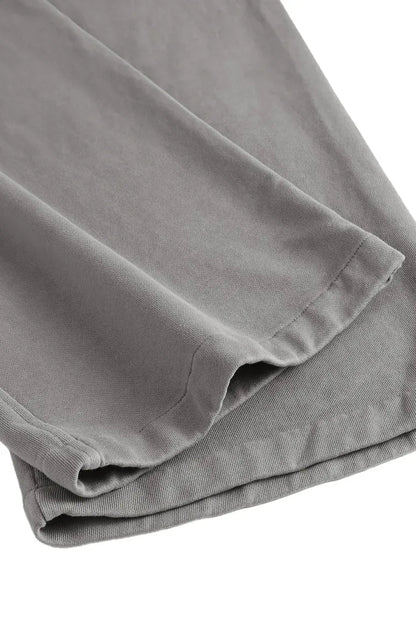 Close-up of folded gray fabric, likely a pair of pants or trousers, showing the texture and hem stitching against a white background.