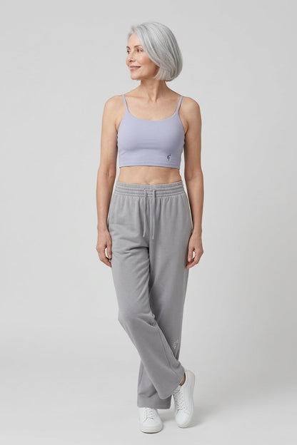 Woman wearing a light purple sports bra and gray sweatpants on a white background