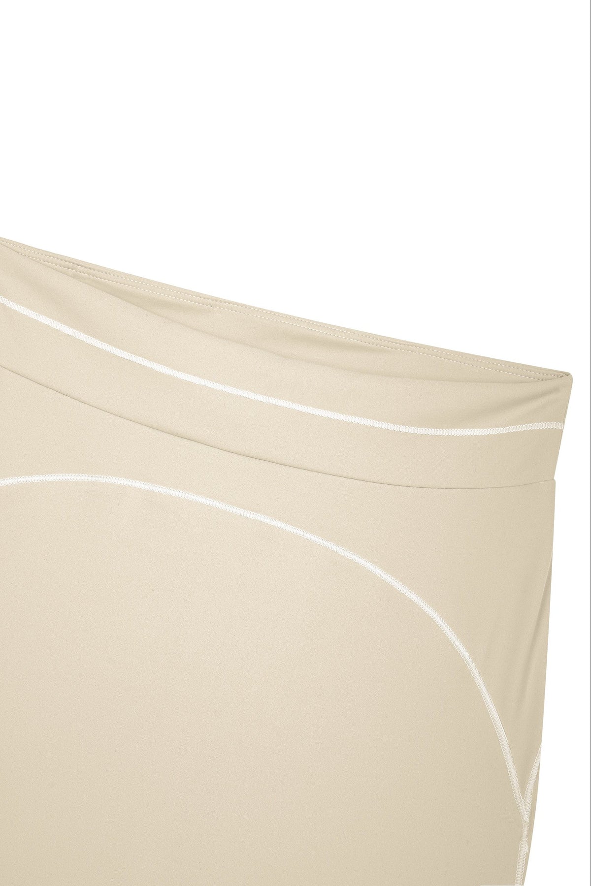 Close-up of a beige garment with white curved piping details on a plain white background.