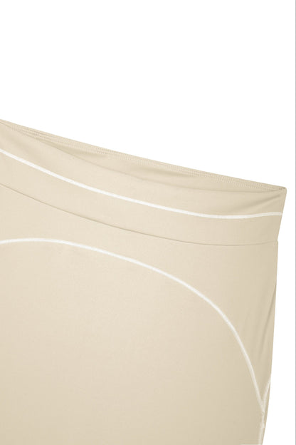 Close-up of a beige garment with white curved piping details on a plain white background.