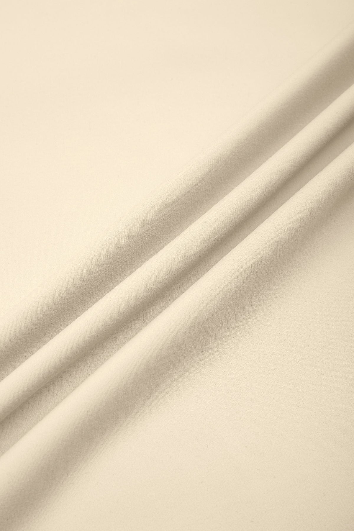 A close-up of draped cream-colored fabric with soft folds and shadows.