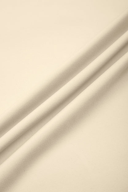A close-up of draped cream-colored fabric with soft folds and shadows.