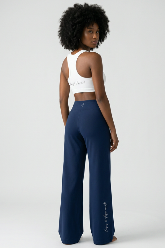 Woman wearing High Rise Pocket Pants in navy blue with a white sports bra, back view, light gray studio background, by Lilliroa