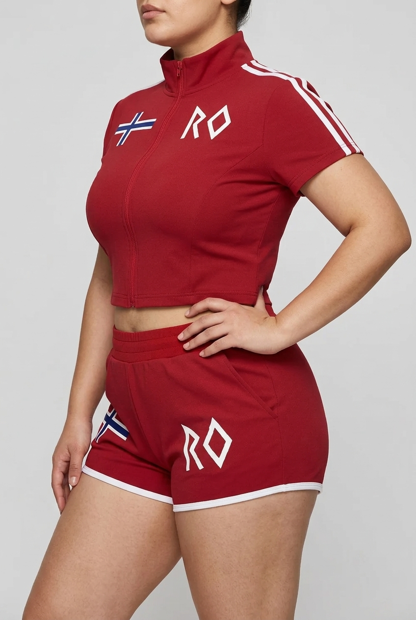 Model wearing a red women's cropped full-zip activewear top and matching athletic shorts with white trim, Norwegian flag detail and RO logo.