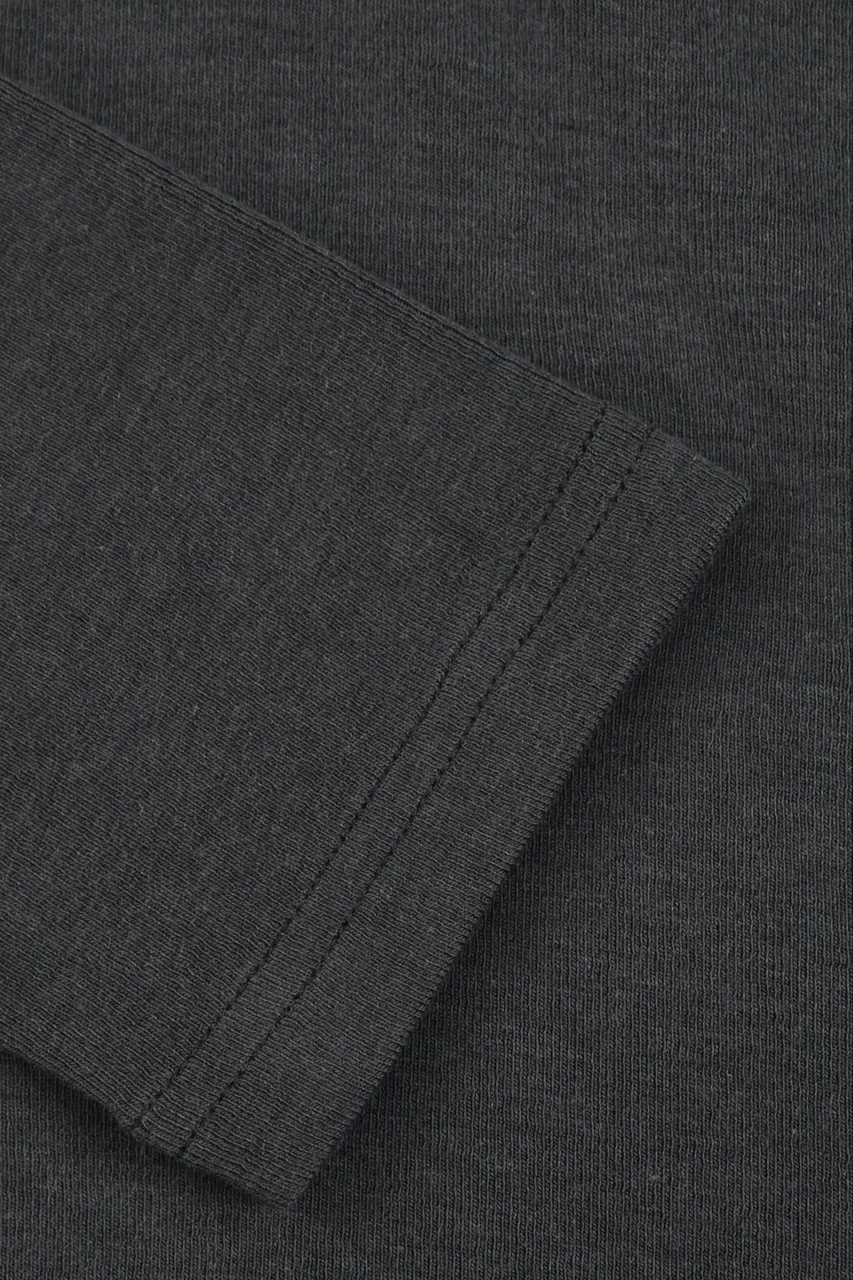 Close-up of a dark charcoal gray ribbed knit fabric, showing a folded cuff or sleeve edge with fine stitching.