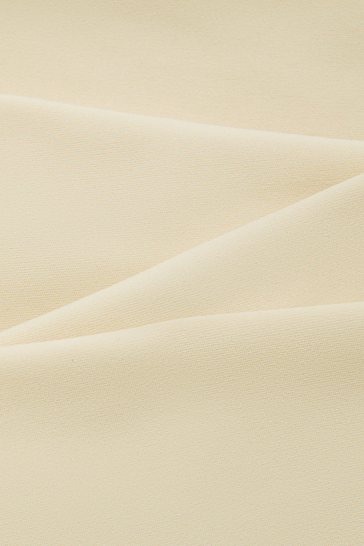 A close-up of draped cream-colored fabric with soft folds and a smooth texture.