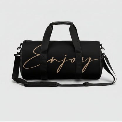 Black gym duffel bag with gold cursive enjoy lettering and adjustable shoulder strap for easy carrying