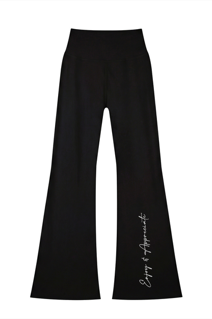 Black high-waisted seamless flared leggings with subtle enjoy and appreciate script detail on the left leg