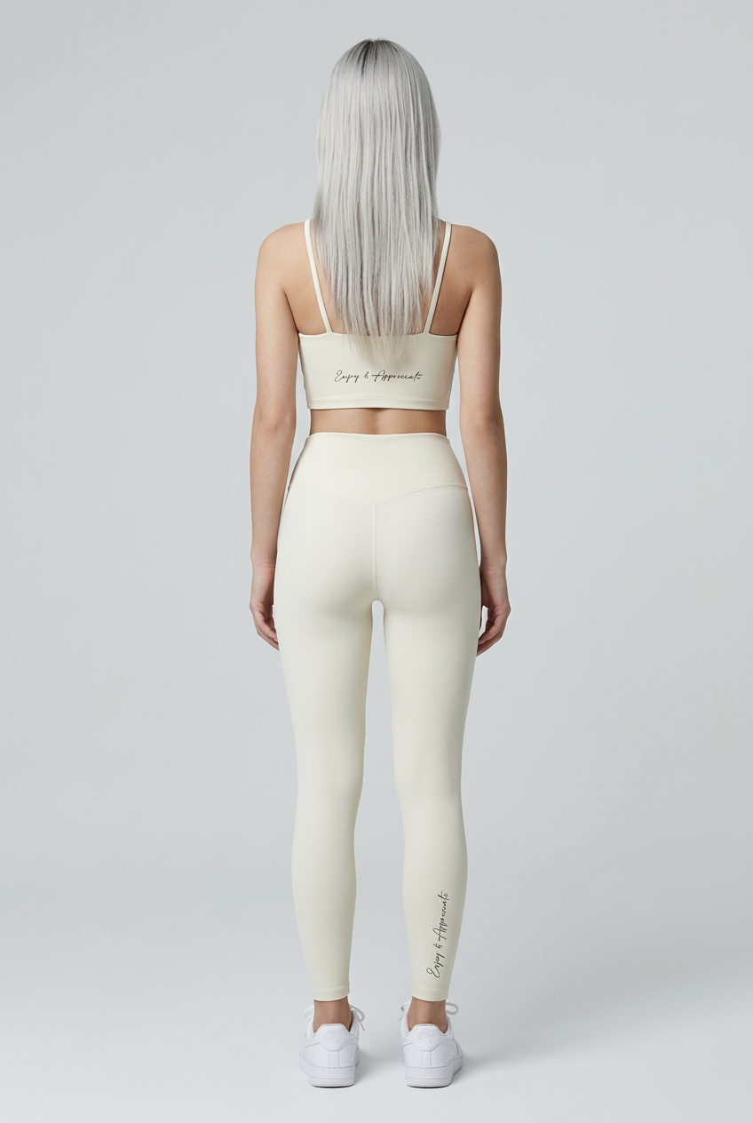 High-waisted seamless cream-colored activewear leggings with subtle texture and embroidered beign and appreciate on back and leg