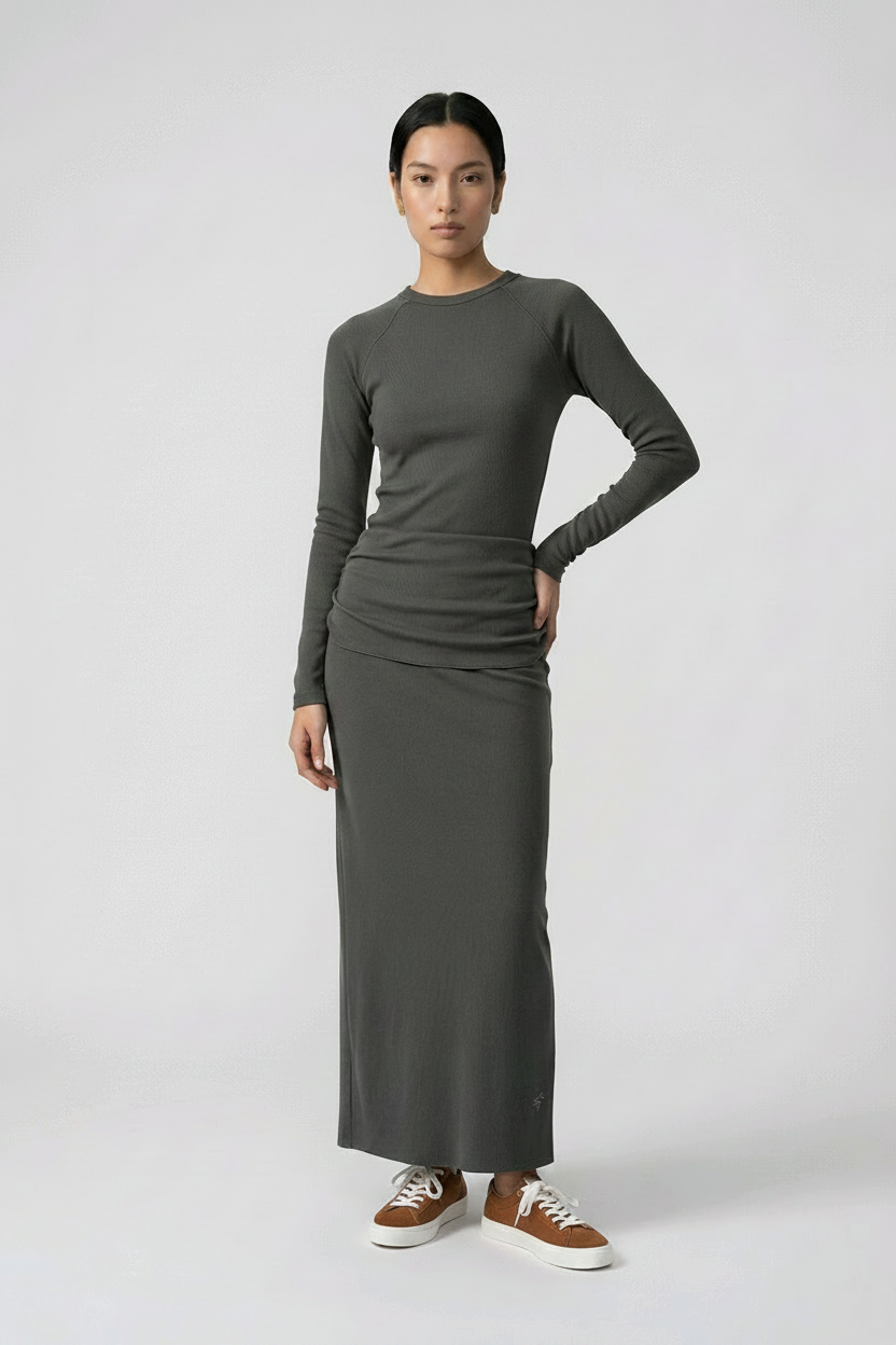 Woman wearing a sleeveless dark grey maxi skirt and sleeveless top on a white background