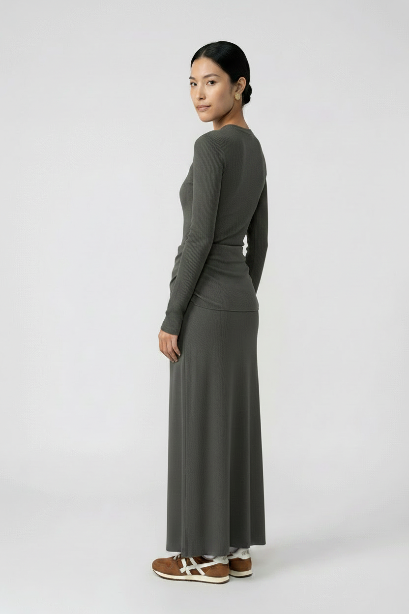 Woman wearing a long, dark gray skirt and a sleeveless top on a white background