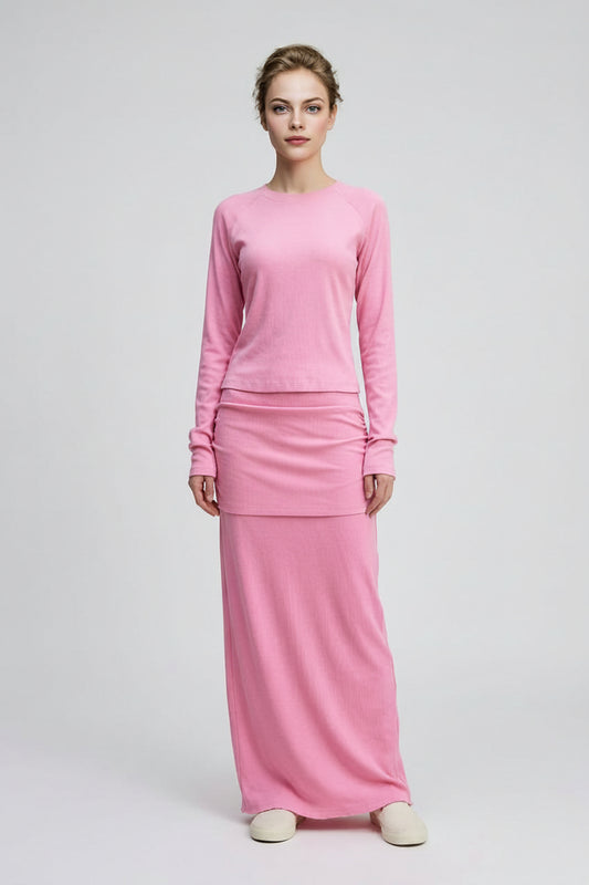 Woman wearing a pink long skirt and long sleeve top on a white background